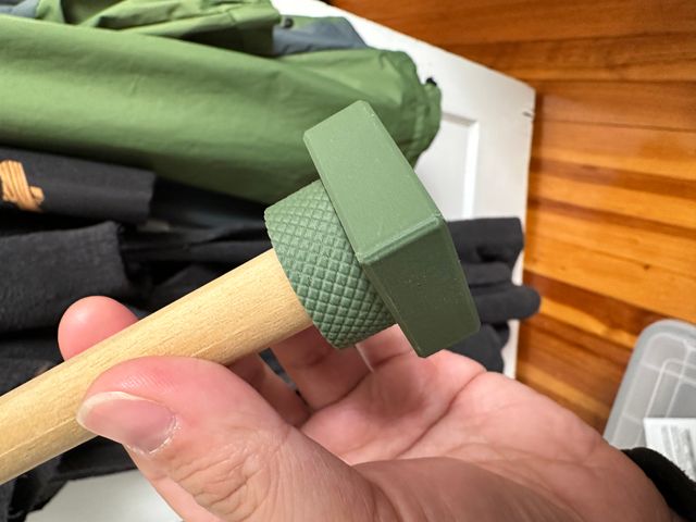 The same wooden dowel attached to the cylindrical object but now the black snap connector is hidden, buried inside of a green box.