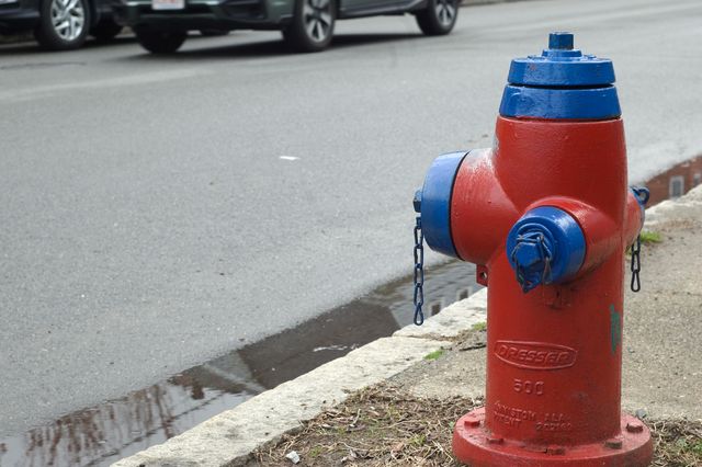 A red fire hydrant with a blue top and arms on a rainy day.