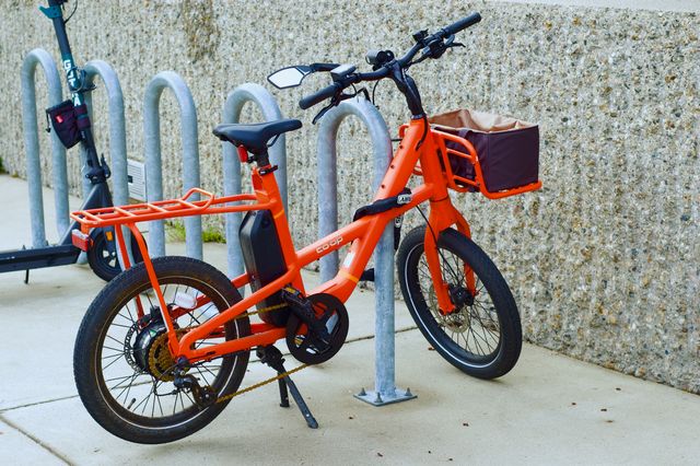 An orange bike against a speckled concrete wall. The image has a soft smooth quality.