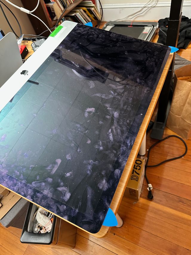 iMac with a handful of blue plastic shaped like guitar picks inserted at various points around the edge of the displace, separating the glass from the aluminum.