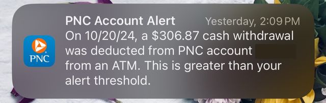 Screenshot of a phone notification reading "PNC Account Alert. On 10/20/24, a $306.87 cash withdrawal was deducted from PNC account from an ATM. This is greater than your alert threshold."