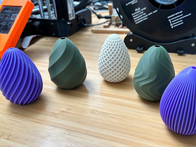 Five easter eggs with various textured outer patterns in assorted colors: purple, sage green, and white.