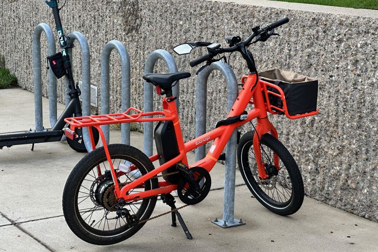 An orange bike against a speckled concrete wall. The speckling on the wall behind the bike is pronounced.
