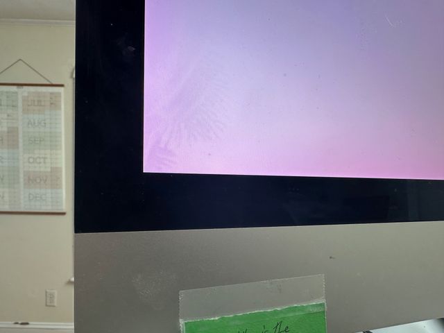 A corner of the imac screen showing a white pixel field. There's a pinkish tint at the edges and a slightly darkened splotch.