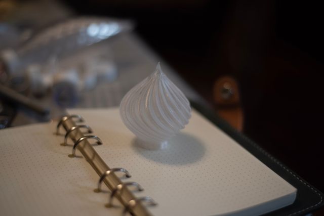 A short clear plastic ornament standing on its base. The top comes to a point, like the end of a radish.