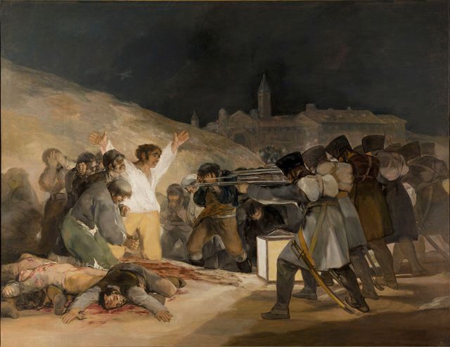 An oil on canvas painting depicting a row of soldiers dressed in 1800s clothing pointing guns at a crowd against a wall. On the ground are several bodies lying on a splash of blood. Some in the crowd have their head in their hands, others look on. One man in the center in a bright white shirt is looking at the soldiers with his arms raised and splayed.
