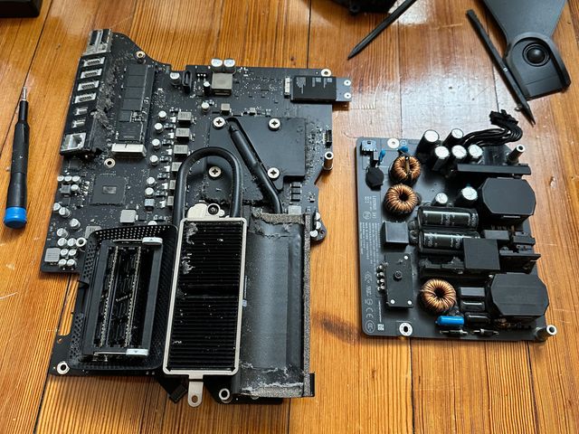 Two large black and silver circuitboards. One has ports and a large grill attached. The other has copper coils and large capacitors.