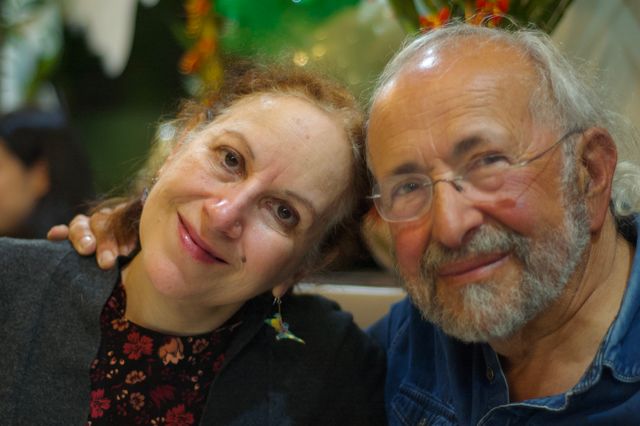 An older white woman with red hair and an older white man, side by side, with their heads inclined together. They're posing for the camera and smiling slightly.