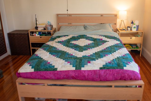 A wide view of the bed frame, showing matching bamboo nightstands on either side.