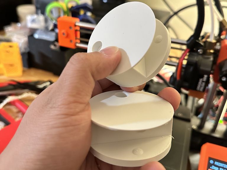 Two white cylindrical plastic objects with a slot through their middle and a divot on one side.